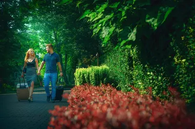 a man and woman walking down a path with their luggage at Zacisze Nad Nidą Resort in Pińczów