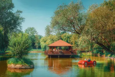 a red car in front of a gazebo on a river at Zacisze Nad Nidą Resort in Pińczów