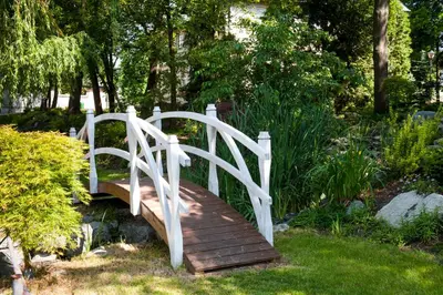 a wooden bridge over a wooden path in a garden at Zacisze Nad Nidą Resort in Pińczów