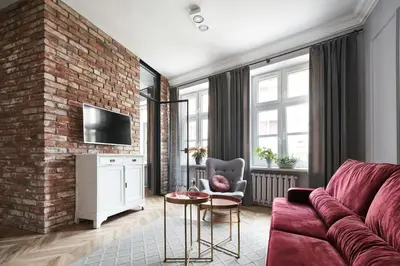 a living room with a red couch and a brick wall at Apartamenty Józefa Kazimierz in Kraków