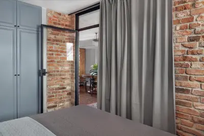 a bedroom with a bed and a brick wall at Apartamenty Józefa Kazimierz in Kraków