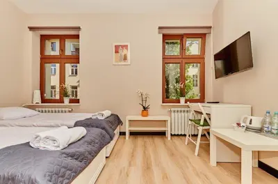 a bedroom with two beds and a desk and a television at Pokoje U Filipa in Kraków