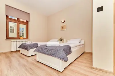 two beds in a white bedroom with wooden floors at Pokoje U Filipa in Kraków