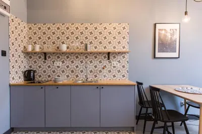 a kitchen with white cabinets and a table with chairs at 19Rooms in Kraków