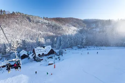 a group of people on a ski lift in the snow at Pokoje na stoku Czarny Groń in Rzyki