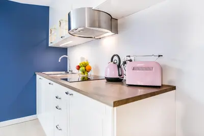 a kitchen with white cabinets and a pink appliance at Krakow Central Apartments in Kraków