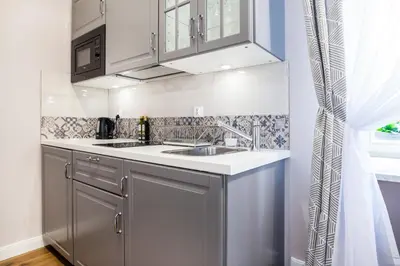 a kitchen with white cabinets and a sink and a window at Krakow Central Apartments in Kraków