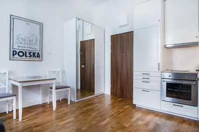 a kitchen with white cabinets and a table and a desk at Krakow Central Apartments in Kraków
