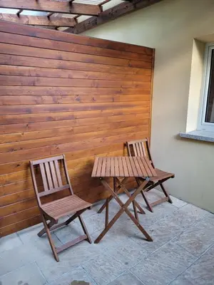 two chairs and a bench next to a wooden wall at Zajazd Wernyhora in Sułoszowa