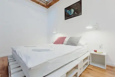 a white bedroom with a large bed with white sheets at City Center Apartment by CityBeat in Kraków