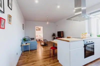 a kitchen and living room with white walls and wooden floors at City Center Apartment by CityBeat in Kraków