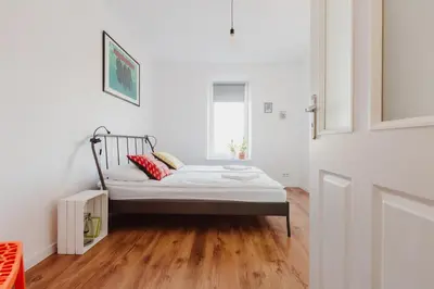 a bed in a room with white walls and wooden floors at City Center Apartment by CityBeat in Kraków