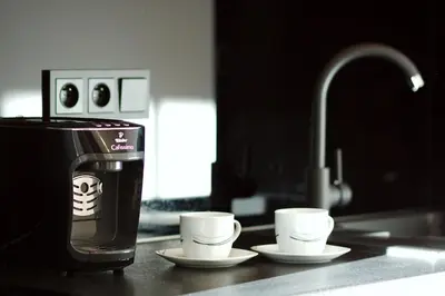 a coffee maker and three cups on a kitchen counter at Aparthotel BC 29 Residence in Kraków