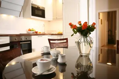 a glass vase with flowers on a table in a kitchen at MJZ Apartments Old Town Krakow in Kraków
