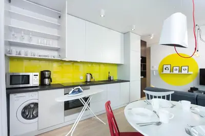 a kitchen with white cabinets and a table and a laundry machine at LEMIR Apartments Wawrzyńca 21 in Kraków