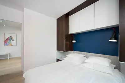 a bedroom with a large white bed with a blue wall at LEMIR Apartments Wawrzyńca 21 in Kraków