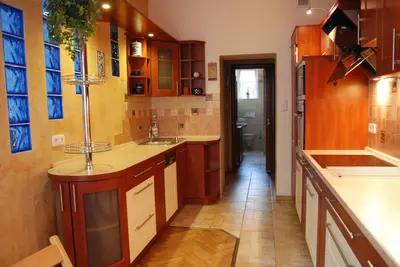 a large kitchen with wooden cabinets and a hallway at Excellent apartment with balcony in Kraków