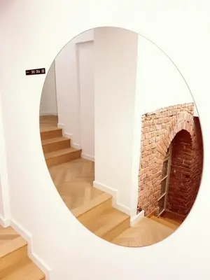 a room with a brick fireplace in a round mirror at St Agnes Apartments Attic in Kraków