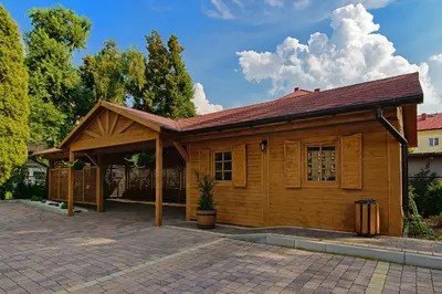 a wooden cabin with a roof on a driveway at Villa Astra - Apartments & Restaurant in Oświęcim