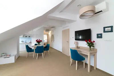 a living room with a dining room table and blue chairs at Villa Astra - Apartments & Restaurant in Oświęcim