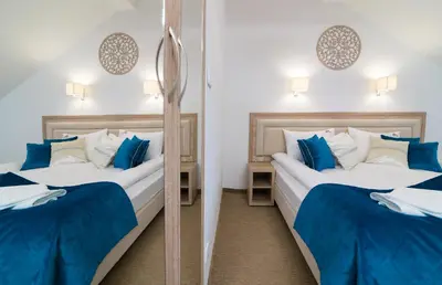 two beds in a room with a mirror at Villa Astra - Apartments & Restaurant in Oświęcim