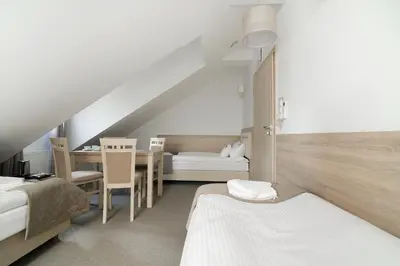 a attic room with two beds and a table at Villa Astra - Apartments & Restaurant in Oświęcim