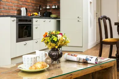 a table with a vase of flowers and a plate of food at Old Town Brigue Apartment by Otium in Kraków