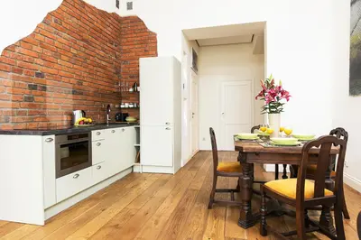 a kitchen with a table and a brick wall at Old Town Brigue Apartment by Otium in Kraków