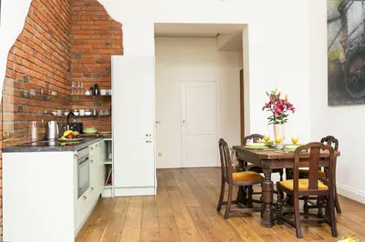 a kitchen with a table and a brick wall at Old Town Brigue Apartment by Otium in Kraków