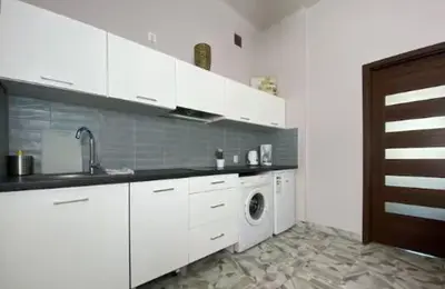 a kitchen with white cabinets and a washing machine at Krakow For You Budget Apartments in Kraków