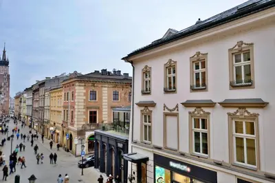 a city street with buildings and people walking down a street at Krakow For You Budget Apartments in Kraków