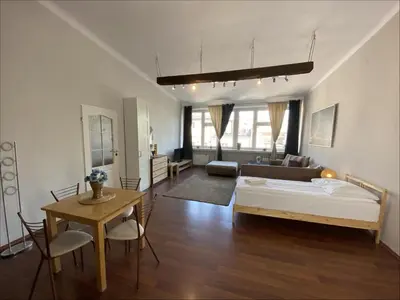 a bedroom with a bed and a table and a living room at Krakow For You Budget Apartments in Kraków