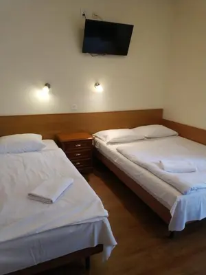two beds in a room with a tv on the wall at Hotel Górsko in Wieliczka