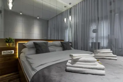 a bedroom with a bed with white sheets and a window at Glossy Apart W21 in Kraków