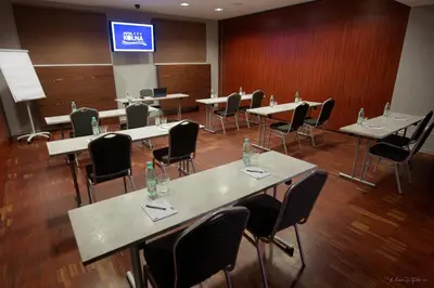 a conference room with tables and chairs and a screen at Hotel Kolna - darmowy parking, basen w cenie in Kraków