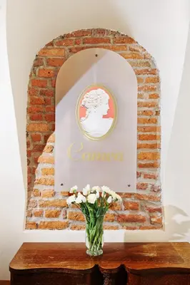 a vase of flowers on a table with a sign on a brick wall at Aparthotel Camea in Kraków