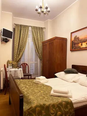 a bedroom with two beds and a table and a window at Aparthotel Camea in Kraków