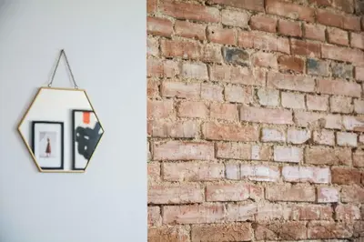 a mirror hanging on a wall next to a brick wall at LION apartments - SILVER in Kraków