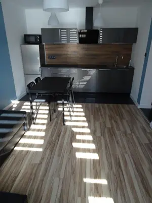 a dining room with a table and chairs on a wooden floor at Blue Apartment Oświęcim in Oświęcim