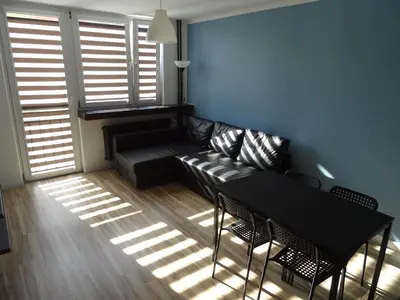 a living room with a black couch and a table at Blue Apartment Oświęcim in Oświęcim