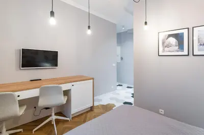 a bedroom with a desk and a tv on a wall at Welcome Apartment - Old Town in Kraków