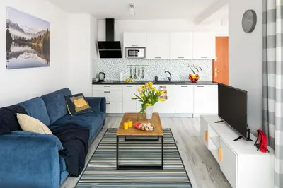 a living room with a blue couch and a kitchen at Green Garden Residence in Kraków