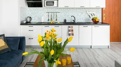 a kitchen with white cabinets and a vase of yellow flowers at Green Garden Residence in Kraków
