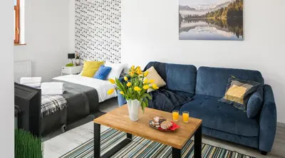 a living room with a blue couch and a table with flowers at Green Garden Residence in Kraków