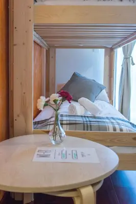 a vase of flowers on a table next to a bed at Harmony Hostel in Zator