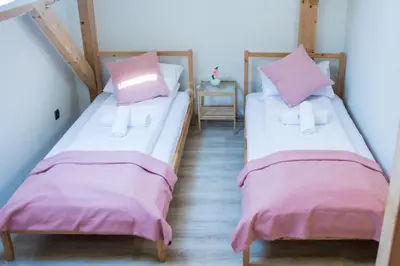 two beds in a room with pink sheets and pillows at Harmony Hostel in Zator