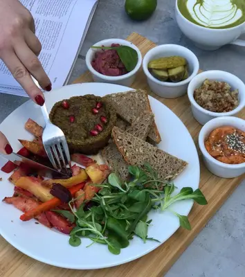 a plate of food with a person holding a fork at Bed&Bath Luxury Apartments in Kraków