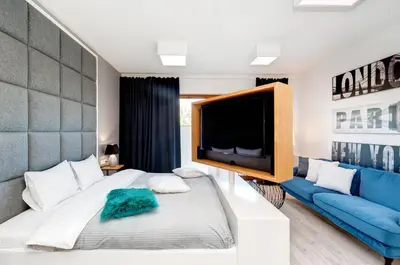 a bedroom with a large television and a couch at Bed&Bath Luxury Apartments in Kraków