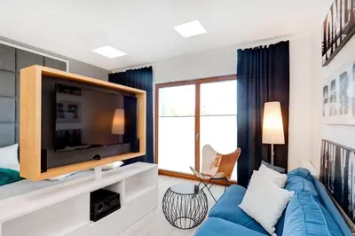 a living room with a blue couch and a tv at Bed&Bath Luxury Apartments in Kraków