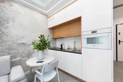 a white kitchen with a table and a refrigerator at Bed&Bath Luxury Apartments in Kraków